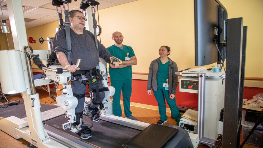 Patient walking on a treadmill with the help of three nurses