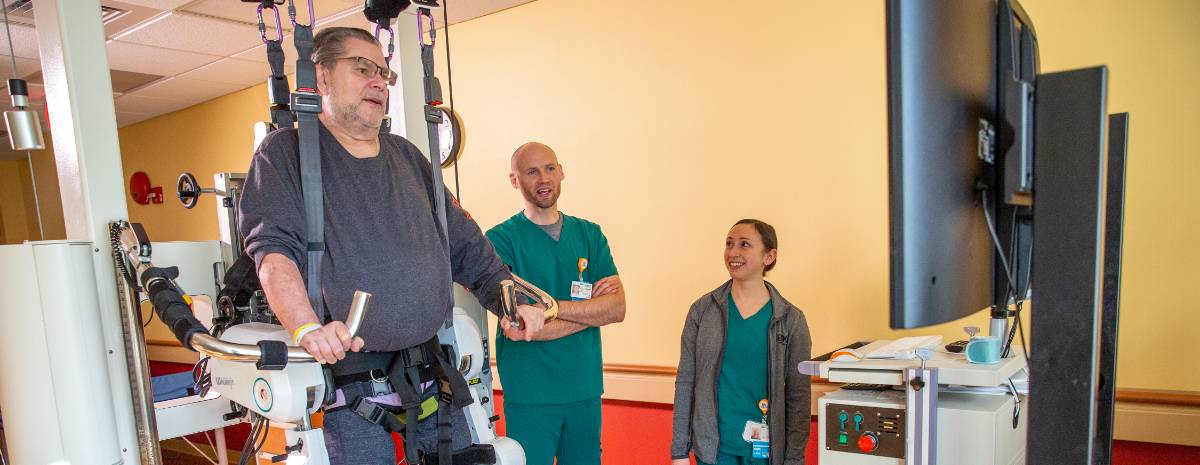 Group of physical therapists helping patient with leg braces walk on a treadmill