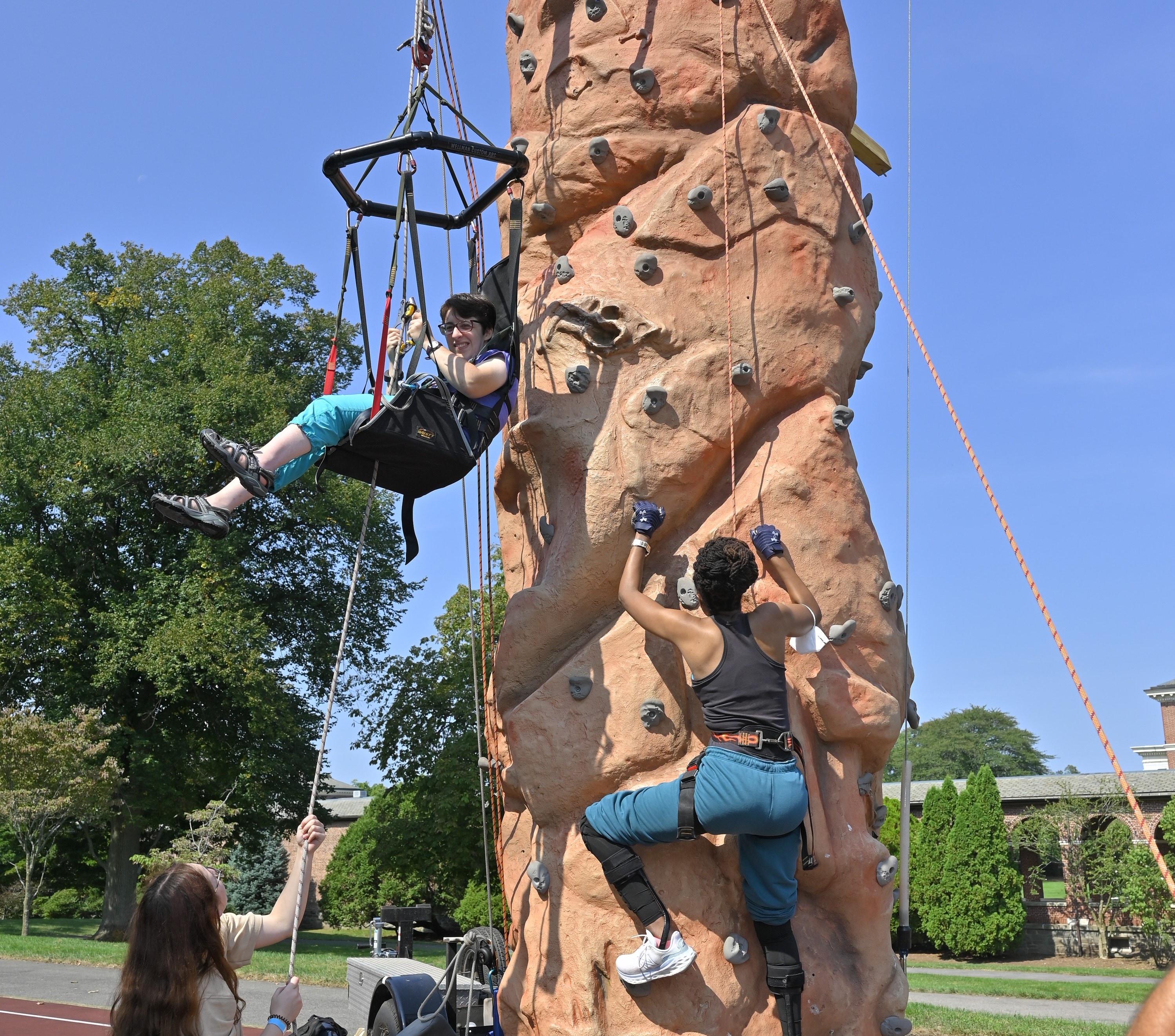 two people rock climbing one in a seat