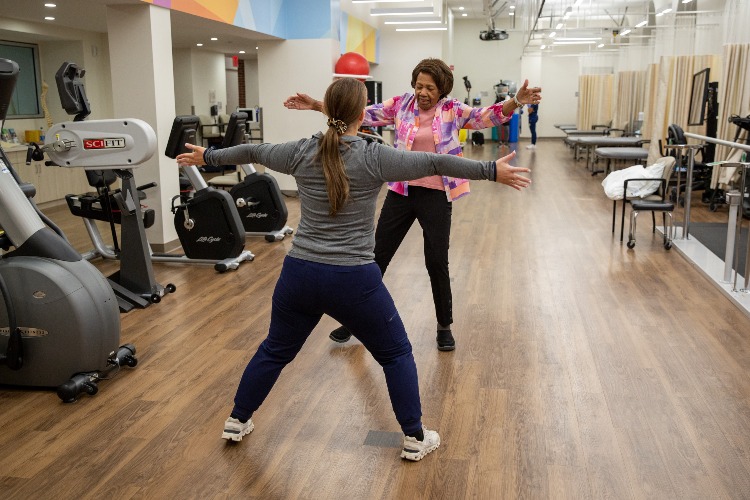 A patient mirrors Burke's staff member's rehabilitation exercise.