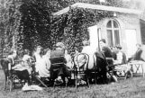 Archival black and white photo of patients and visitor sitting outside, circa 1910s