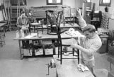 Archival black and white photo of patients in a workshop caning chairs circa 1930s