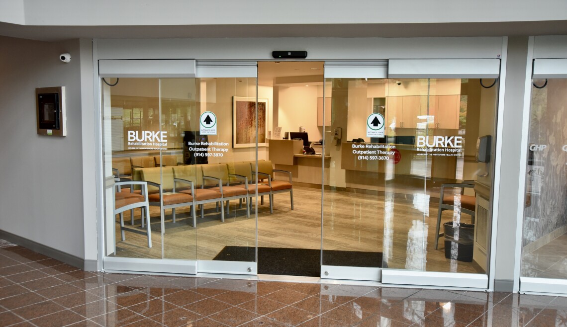 Shows Burke Rehabilitation Outpatient Therapy's glass entry doors and lobby. 